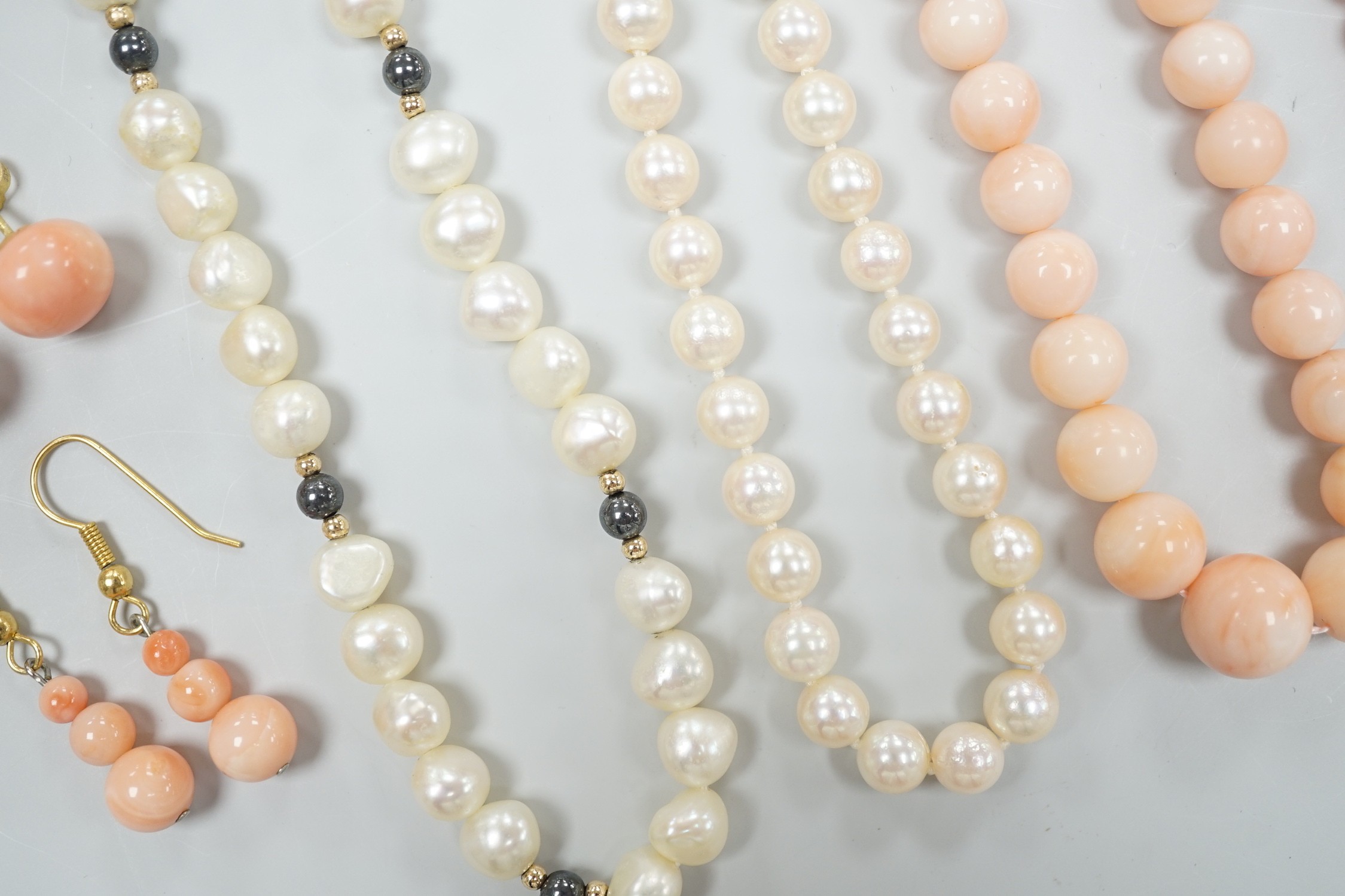 Two modern single strand cultured pearl necklaces, both with 375 clasp, one with hematite beads, longest 42cm, together with two modern coral bead necklaces, one with pair of matching drop earrings.